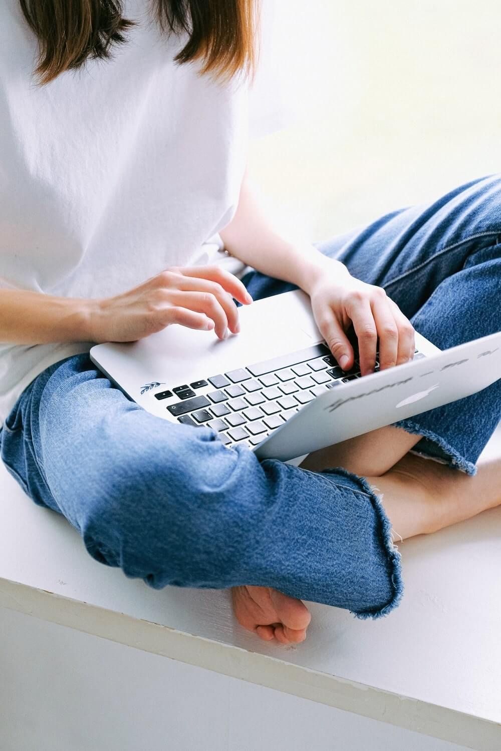 Junge Frau mit Laptop auf dem Schoß